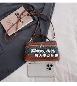 Detail of mini denim and brown leather box bag showing size comparison with a phone