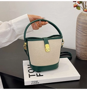 Detail of canvas bucket bag with green leather trim and golden twist lock closure