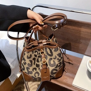 Chic leopard print drawstring bucket bag with brown leather trim and adjustable strap