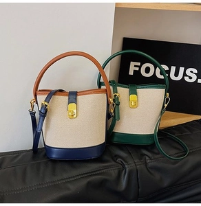 Detail view of canvas bucket bags with leather trim, stitching, and metal buckles