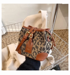 Detail of leopard print bucket bag with drawstring closure and golden metal buckle