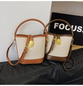 Detail of canvas bucket bags with contrast leather trim and golden metal buckles