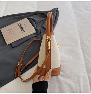 Detail of canvas bucket bag with brown leather trim and golden metal clasp on soft bedding