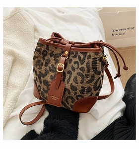 Detail of leopard print drawstring bucket bag with leather trim and gold buckle accent
