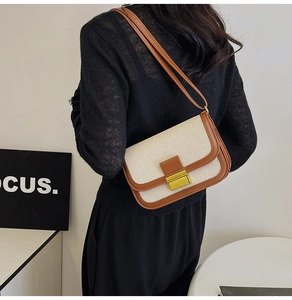 Close-up of vintage stitch detail and gold square buckle on beige canvas shoulder bag