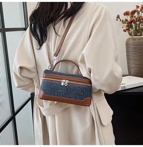 Detail shot of denim and brown leather crossbody bag worn by model in cozy interior setting