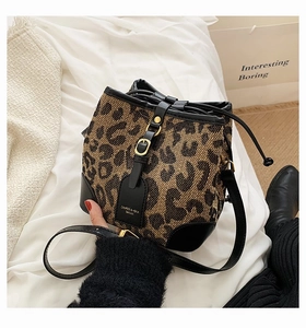 Close-up of leopard print drawstring bucket bag with black leather straps and gold hardware