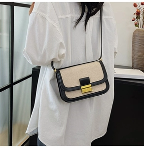 Detail of vintage beige woven crossbody bag with black trim worn by a model in a studio