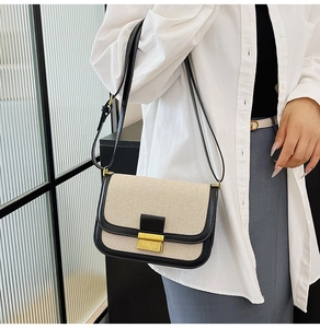 Detail of minimalist stitching and gold metal buckle on a two-tone crossbody bag