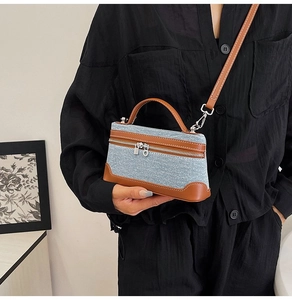 Close-up of denim and brown leather patchwork handbag with silver zipper and stitching