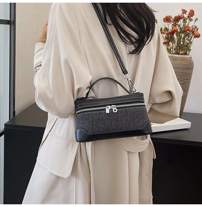Detail of dark tweed crossbody bag with black leather trim and white contrast stitching