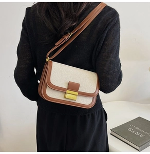 Detail of vintage flap bag in beige canvas and brown leather with gold metal buckle clasp