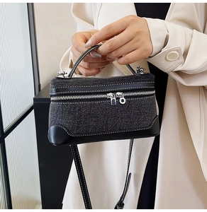 Detail of vintage denim patchwork handbag featuring white stitching and silver dual zippers