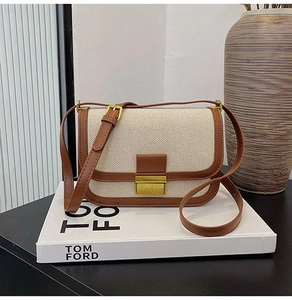 Close-up of beige canvas and brown leather stitching detail with gold metal buckle