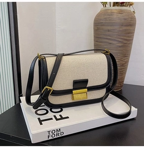 Close-up of cream woven fabric and black leather trim on a retro crossbody bag