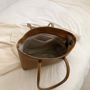 Interior view of brown leather tote bag showing spacious main compartment and zipper pocket