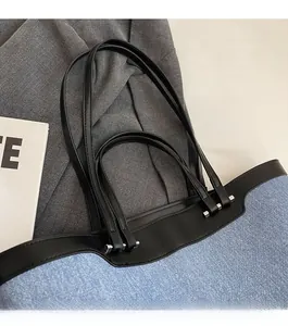 Detail of blue denim tote bag with black leather straps and silver metal hardware
