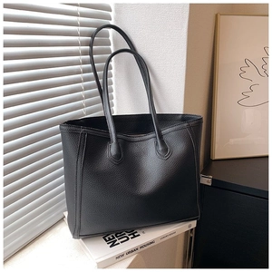 Detail of black lychee grain leather texture on tote bag with soft natural light