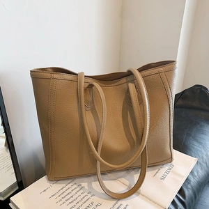 Detail of khaki pebbled leather tote bag with sturdy shoulder straps on a magazine