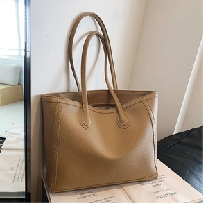 Detail of khaki tote bag showing pebbled leather texture and minimalist shoulder strap design