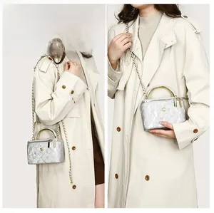 Close-up of silver quilted crossbody bag featuring golden top handle and chain strap