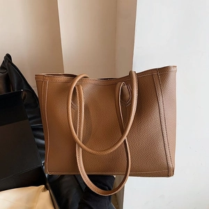 Detail view of the brown lychee pattern leather tote bag showing fine stitching and texture