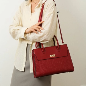 Detail of red leather tote featuring exotic croc texture, gold clasp, and handle
