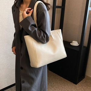 Detailed view of beige faux leather tote bag showing fine pebble grain texture and stitching