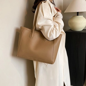 Close-up of brown litchi pattern faux leather tote bag showing texture and slim handles