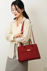 Detail of red lychee pattern tote bag with gold twist-lock and shoulder strap on model
