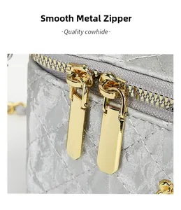 Close-up of golden dual zippers and diamond quilt pattern on silver cowhide handbag