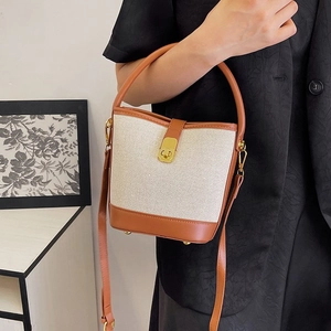 Minimalist canvas and brown leather bucket bag with gold clasp and adjustable strap