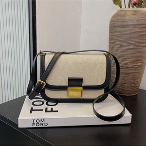 Retro canvas crossbody bag with black leather trim and golden buckle on white display