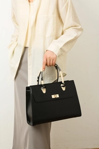 Close-up of black snakeskin-pattern tote bag featuring a gold lock and patterned handle