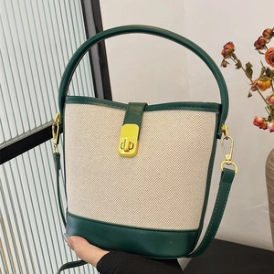 Chic canvas bucket bag with green leather trim and gold twist lock in hand