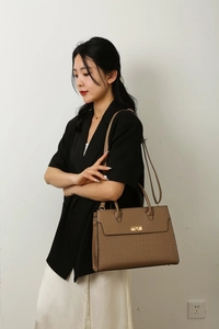 Close-up of brown crocodile embossed tote bag with gold twist lock and dual handles