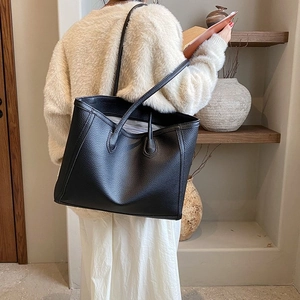 Rear view of a model wearing the black pebbled leather tote bag with long shoulder straps