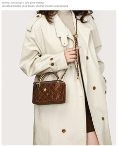 Close-up of brown quilted leather handbag with gold metal handle on a model in a trench coat