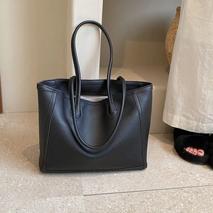 Close-up of black lychee grain leather tote bag showing fine stitching and twin top handles