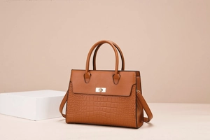 Detail of a brown lychee pattern tote bag showing faux crocodile leather texture and lock
