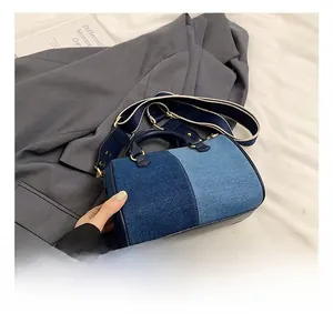 Détail du sac Boston en jean bicolore avec garniture en cuir et large bandoulière textile