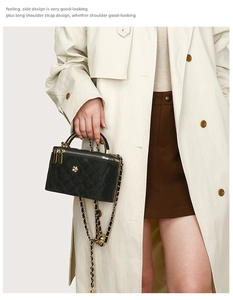 Detail of black quilted shoulder bag with gold chain strap and elegant metal clasp