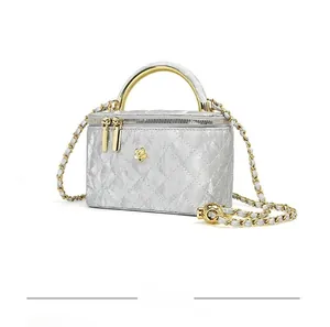Macro view of silver quilted vanity bag with golden camellia hardware and chain strap