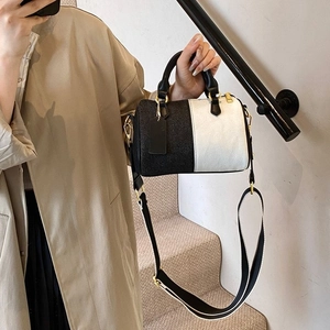 Sac à main Boston bicolore avec large bandoulière rayée porté par un mannequin