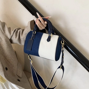 Détail du sac boston en denim et toile avec une large bandoulière en tissu rayé bicolore