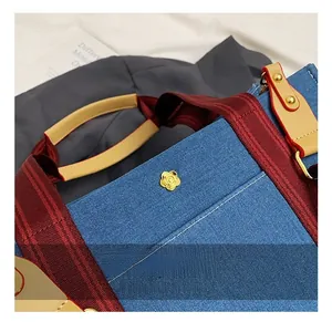 Détail du sac cabas en denim bleu avec boucle fleurie dorée et sangle rayée élégante