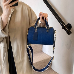 Détails du sac Boston bleu marine avec large bandoulière bicolore et finitions dorées