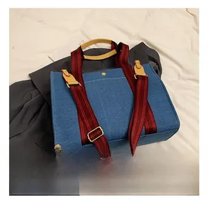 Détail du sac cabas en jean matelassé avec sangle rayée et poignées en cuir et garniture dorée