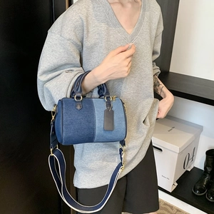 Détail d'un sac Boston en denim bicolore avec fermetures éclair dorées et bandoulière