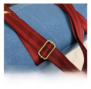 Détail de la bandoulière rayée réglable avec boucles dorées sur le sac en jean tendance